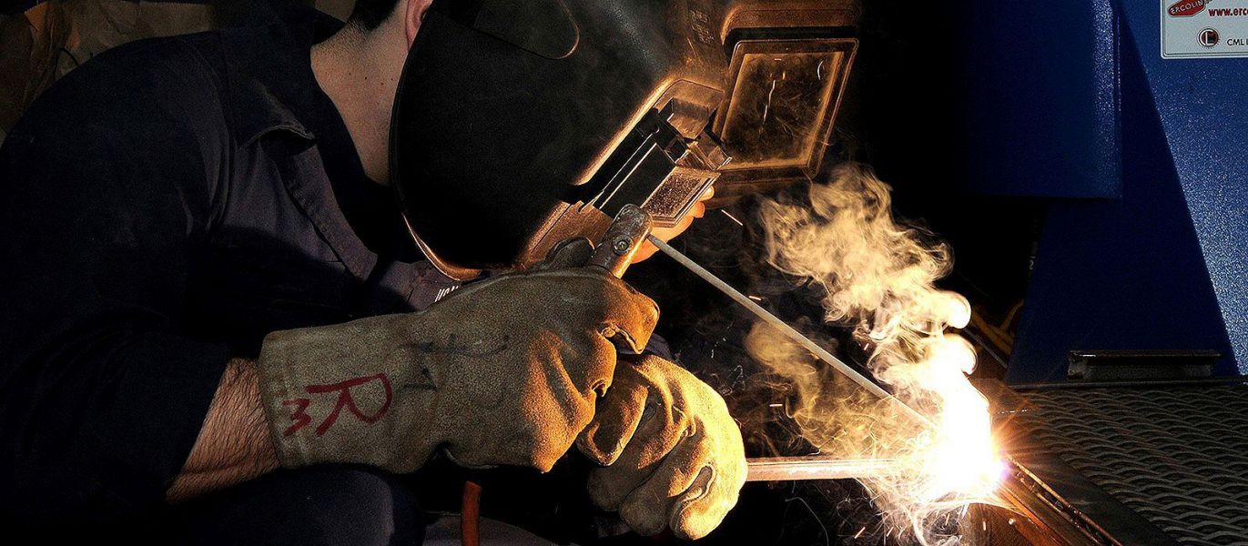 Ein Mann mit Schutzmaske schweißt Metall